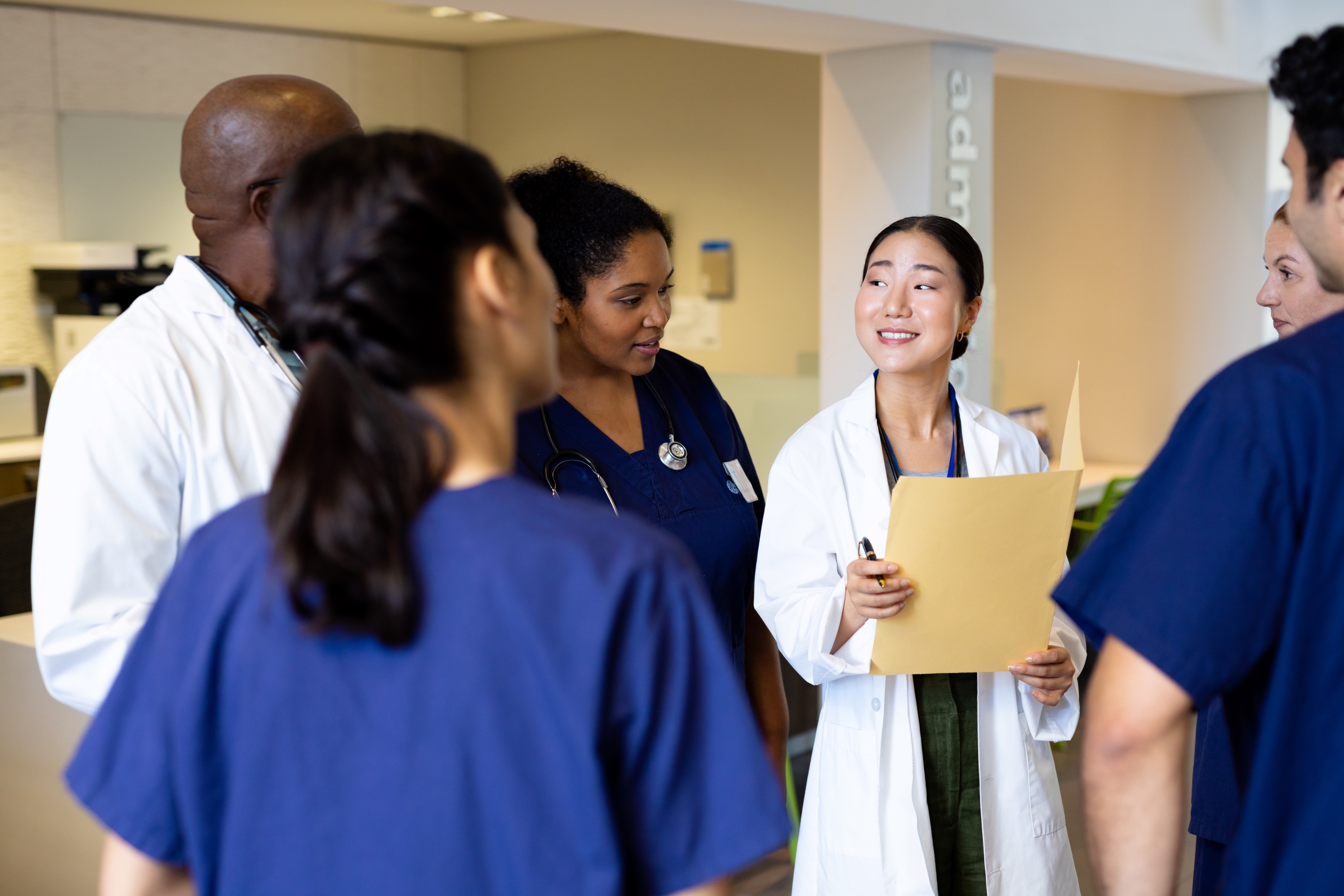 smiling-asian-female-doctor-with-folder-talking-wi-2023-11-27-05-01-27-utc1